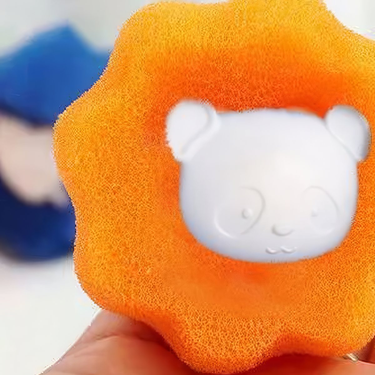 Close-up of an orange pet hair remover ball with its white bear-face center